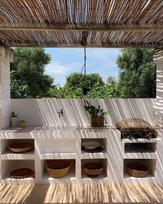 an outdoor kitchen with bamboo roof and shelves