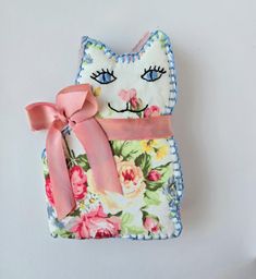 a close up of a cat shaped object on a white surface with flowers and pink ribbon