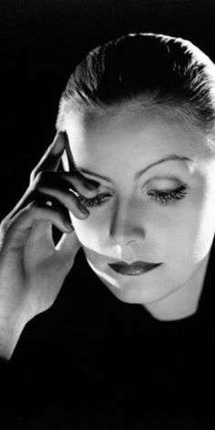 a black and white photo of a woman holding her hand to her face