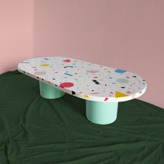 a skateboard sitting on top of a green table in front of a pink wall