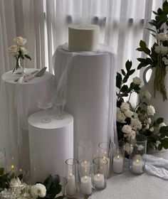 a table topped with lots of white flowers next to tall vases filled with candles