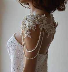 the back of a woman's white dress with pearls and beads on her neck