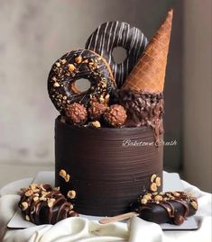 there is a chocolate cake with donuts and other desserts on top of it