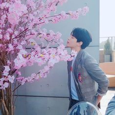 a man standing next to a tree with pink flowers