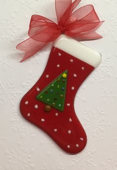 a red christmas stocking with a green tree on it and a red ribbon hanging from the top