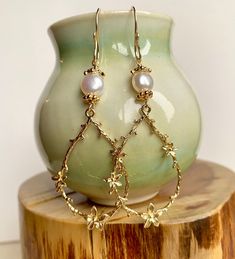 Enhance your boho chic style with this set of long gold teardrop-shaped flower branch dangly earrings. Featuring large gold-plated brass flower branch charms, these earrings are delicately crafted and exude a sweet charm. The handmade earring hooks, crafted with 10K gold-filled wire, add a touch of elegance. At the top, white freshwater pearls with gold-plated floral bead caps provide a classic and timeless accent. Measuring 2 1/2" X 7/8", including the gold-filled wire hooks, these earrings are a beautiful choice for Christmas gifts, birthdays, weddings, or any special occasion. Embrace the allure of boho chic with these intricate and stylish flower branch earrings. Gold Flower Chandelier Earrings Elegant Style, Elegant Teardrop Earrings With Flower Charm, Gold Flower-shaped Elegant Chandelier Earrings, Elegant Gold Flower Chandelier Earrings, Feminine Flower Dangle Earrings With Pearl Drop, Gold Feminine Dangle Flower Earrings, Gold Flower Earrings, Nature-inspired, Elegant Single Teardrop Flower Earring, Nature-inspired Gold Teardrop Pendant Jewelry