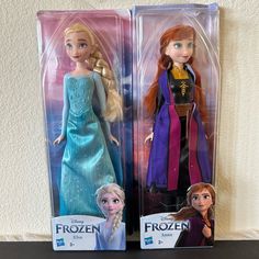 two frozen princess dolls in their packaging on a table with white wall and black countertop