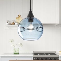 a light that is hanging from a ceiling in a kitchen next to a stove top