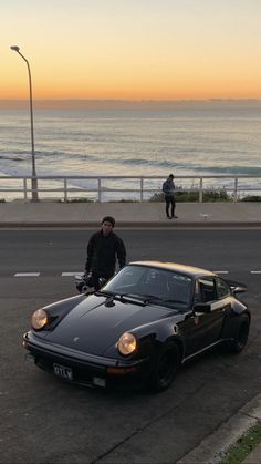 a man riding a bike next to a black sports car