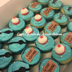 cupcakes with blue frosting and white icing are arranged in a box