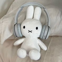 a white stuffed rabbit with headphones on it's ears sitting on a bed