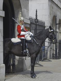 a man riding on the back of a black horse in front of a tall building