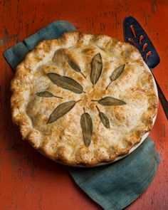 a pie sitting on top of a wooden table next to a knife and fork in front of it