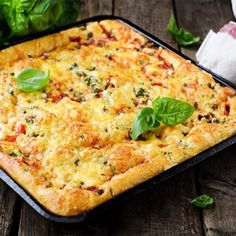 a square casserole dish with spinach and cheese on the top, sitting on a wooden table