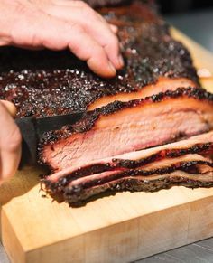 someone cutting up some meat on top of a wooden board