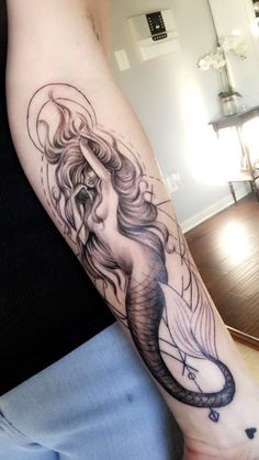 a woman's arm with a tattoo on it and an image of a mermaid