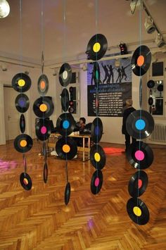 a group of vinyl records hanging from strings in a room with wood floors and wooden flooring