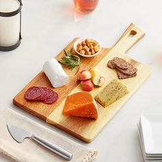 a wooden cutting board topped with cheese and meats