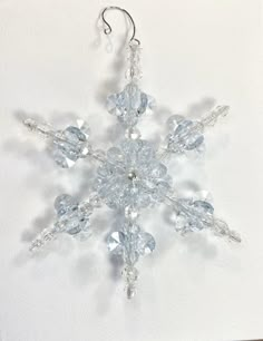 a snowflake ornament hanging from a hook on a white wall in the shape of a star