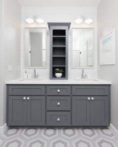 a bathroom with two sinks and gray cabinets