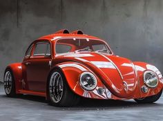 an orange and white vw bug sitting in front of a wall