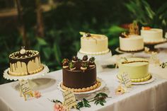 a table topped with lots of cakes covered in frosting