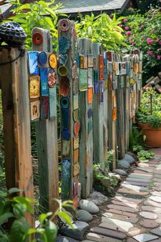 a garden fence made out of old wooden boards and colorful glass tiles on the sides