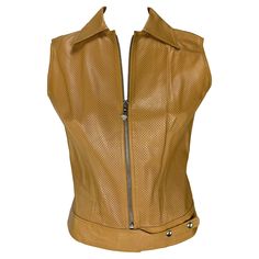 Presenting a tan Versace perforated leather vest designed by Donatella Versace. From the early 2000s, this fabulous vest is constructed of perforated leather, features a collar belted snap waist, and is complete with a silver-tone Versace Medusa zipper pull. Approximate measurements: Size - IT42 Bust: 39" Waist:31" Shoulder to hem: 20.5" 100% leather Versace Blouse, Vest Designs, Donatella Versace, Chic Leather, Perforated Leather, Leather Vest, Gianni Versace, Early 2000s, Vest Top