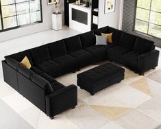 a large black sectional couch sitting on top of a white rug in a living room