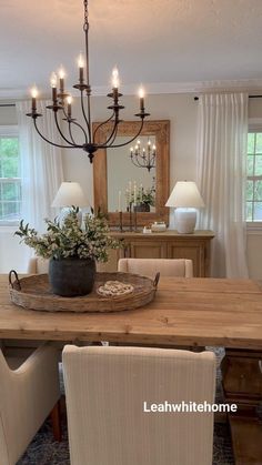 a dining room table with chairs and a chandelier hanging from the ceiling above it