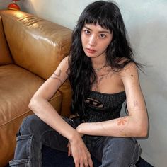 a woman sitting on the floor with her arms crossed and tattoos painted on her chest