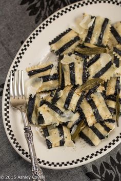 a white plate topped with pasta covered in cheese and green peppers next to a fork