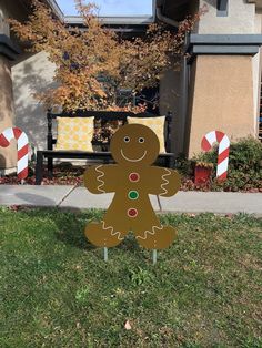 a gingerbread man standing in front of a house with candy canes on the lawn