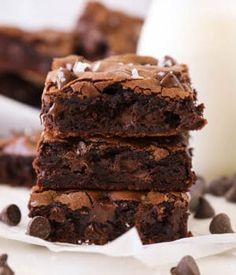 three chocolate brownies stacked on top of each other next to a glass of milk