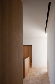 an empty room with wooden furniture and white walls, is shown from the hallway to the bedroom