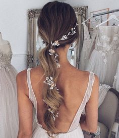 a woman with long hair in a wedding dress looking at her reflection in the mirror