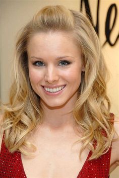 a woman with blonde hair and blue eyes smiles at the camera while wearing a red dress