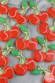 decorated cookies with cherries and green leaves on a marble table top, ready to be eaten