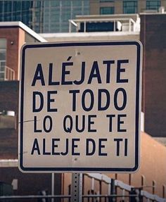 a white street sign with black writing on it in front of some buildings and trees