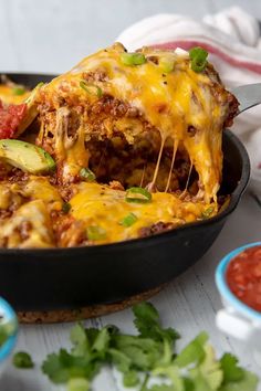 a skillet filled with mexican food and garnished with cilantro sauce