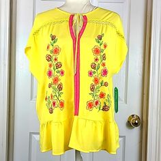 Pioneer Women Blouse Has Cap Sleeves, A Split Neck, W/ Tie, In Bright Yellow W/Pink And Red Embroidery On Front, And Eyelet Lace Trim On Bodice, Ruffle Hemline, Size Medium. Yellow Embroidered Short Sleeve Top For Spring, Embroidered Yellow Summer Blouse, Yellow Short Sleeve Embroidered Casual Top, Casual Yellow Top With Floral Embroidery, Yellow Casual Short Sleeve Embroidered Top, Yellow Embroidered Summer Blouse, Embroidered Yellow Blouse For Summer, Casual Yellow Embroidered Short Sleeve Top, Yellow Embroidered Short Sleeve Blouse