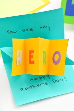 an origami card with the word hero written on it and two pieces of folded paper