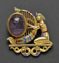 a gold brooch depicting an egyptian harp player