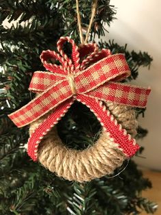 an ornament hanging from a christmas tree with red and white ribbons on it