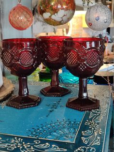 three red glass goblets sitting on top of a blue table