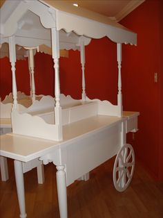 a white dollhouse bed sitting on top of a hard wood floor next to a red wall