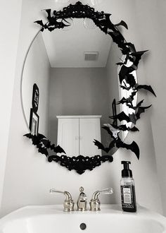 a bathroom sink with a mirror above it that has bats on it and a bottle of lotion next to it