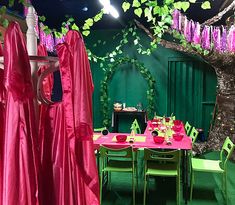 a green room with tables and chairs covered in pink cloths