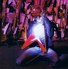 a man sitting on the floor with his guitar in front of him, holding an electric guitar