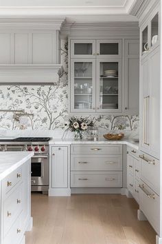 a kitchen with white cabinets and floral wallpaper